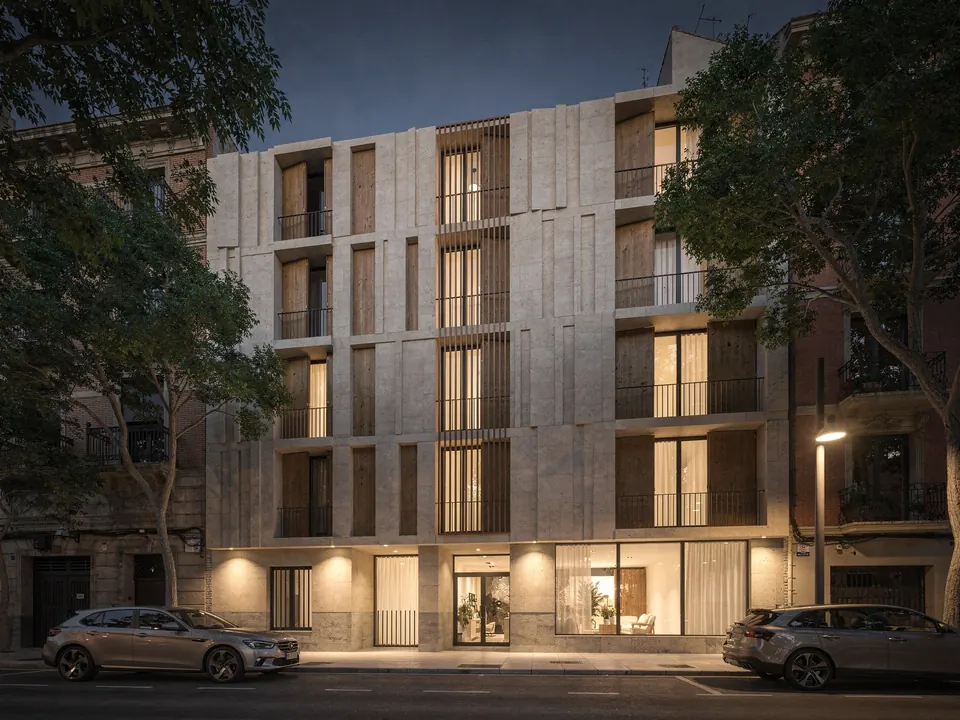 Edificio residencial urbano con fachada de piedra y contraventanas de madera al anochecer